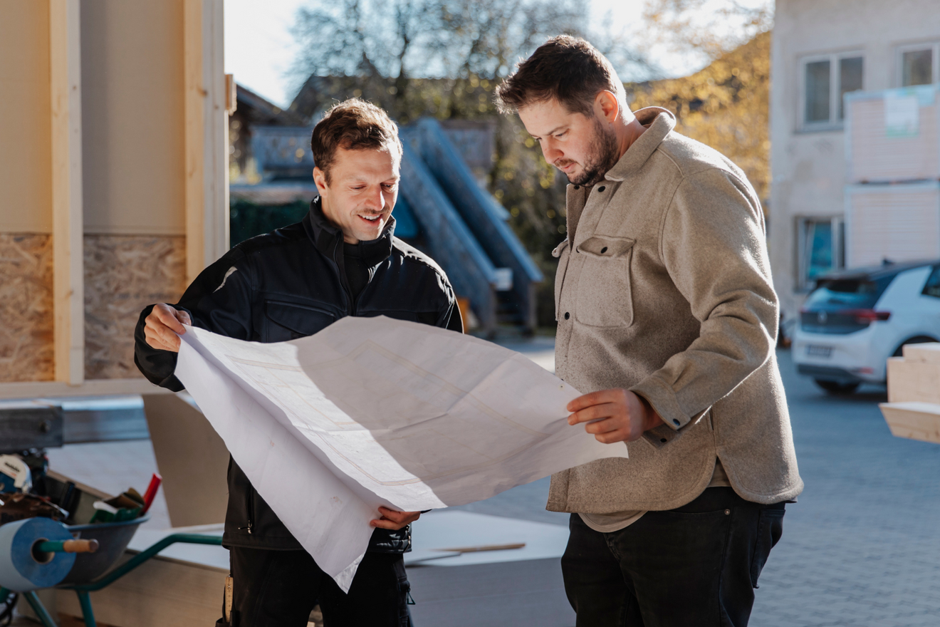 Florian Huber und ein weiterer Mann sehen sich gemeinsam einen Bauplan an.