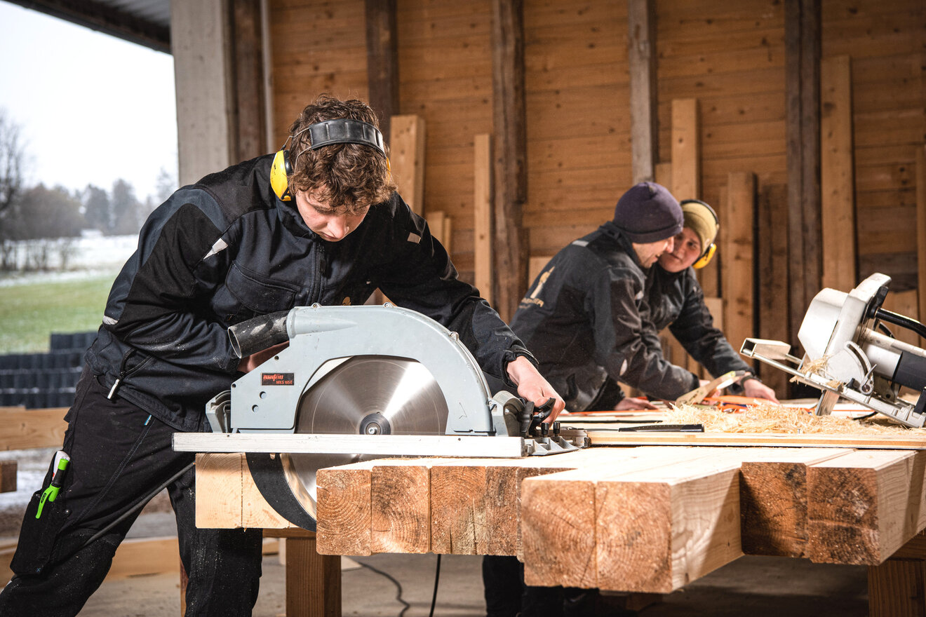 Zwei Gesellen der Zimmerei Huber bei der Arbeit an der Säge.